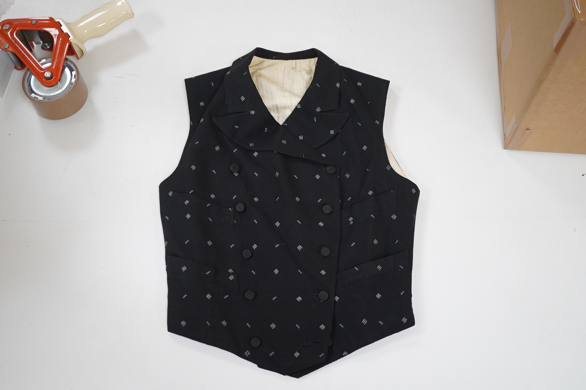 An Edwardian small gentleman’s double breasted waistcoat, made from black woven wool, with a sprig design, under arm chest 36inches. Condition - lining has various rust marks, the waistcoat would benefit dry cleaning